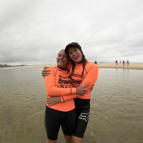 Two friends hugging after a surfing lessons
