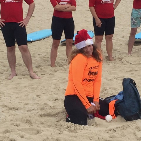 A surfer wearing a santa hat posing for a picture