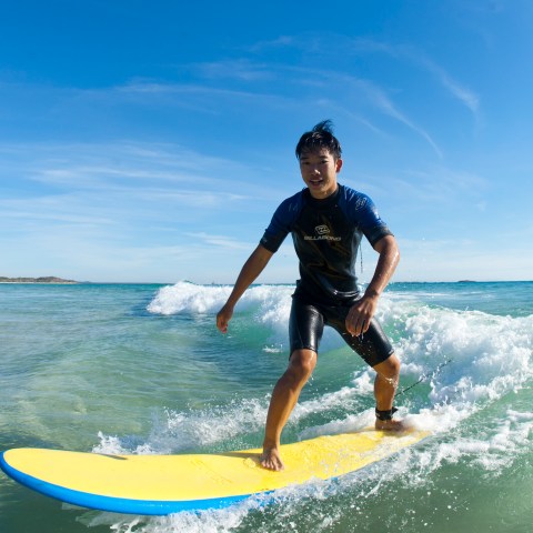 A young surfer all smiles as he rides a wave