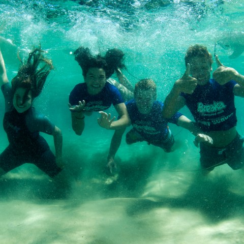 A group of surfers posing for a picture underwater