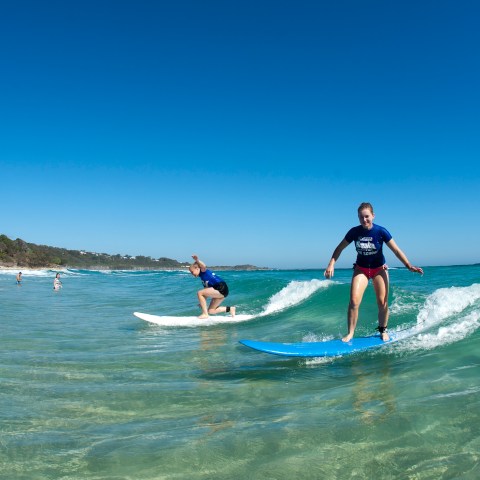 Two girls riding a wave as they get a hang of it